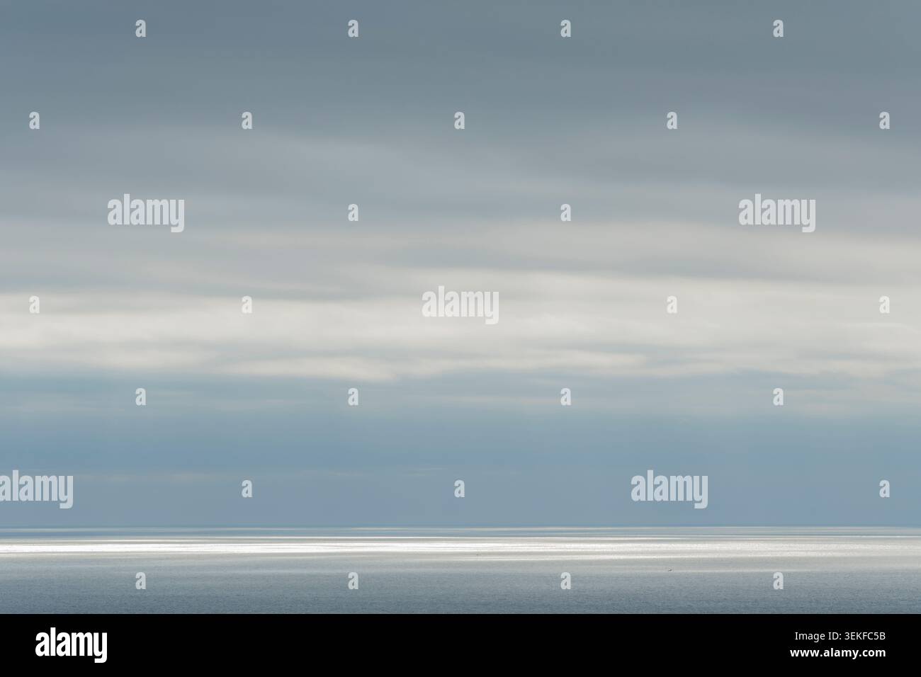 LA LUMIÈRE DU SOLEIL BRILLE À TRAVERS UNE COUVERTURE DE STRATUS NUAGES AU-DESSUS DE LA MER Banque D'Images