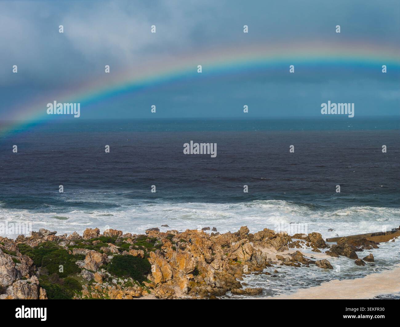 Cape Town côte Atlantique avec arc-en-ciel sur les vagues de l'océan foncées et agitées Banque D'Images