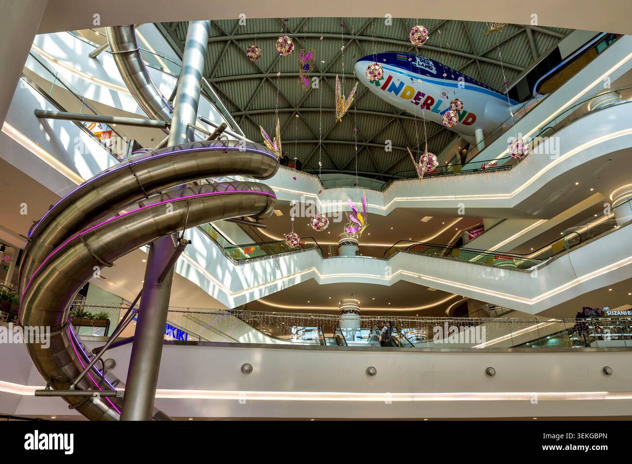 Atrium à plusieurs niveaux du centre commercial Deniz avec une glissière en spirale en acier inoxydable et des ornements décoratifs suspendus. Bakou, Azerbaïdjan. Banque D'Images