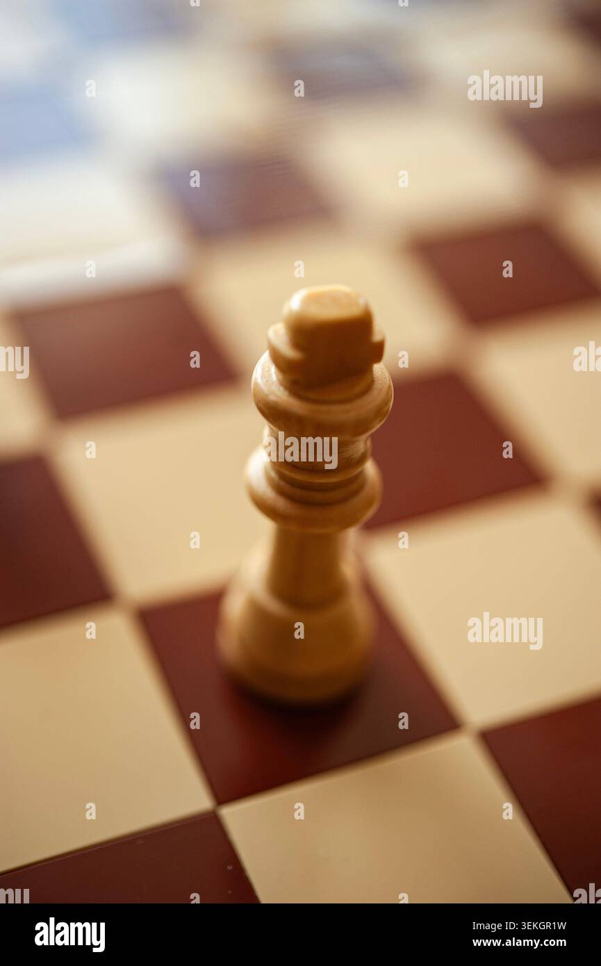 Roi d'échecs en bois seul sur échiquier, lumière chaude et mise au point peu profonde, concept de stratégie minimaliste Banque D'Images