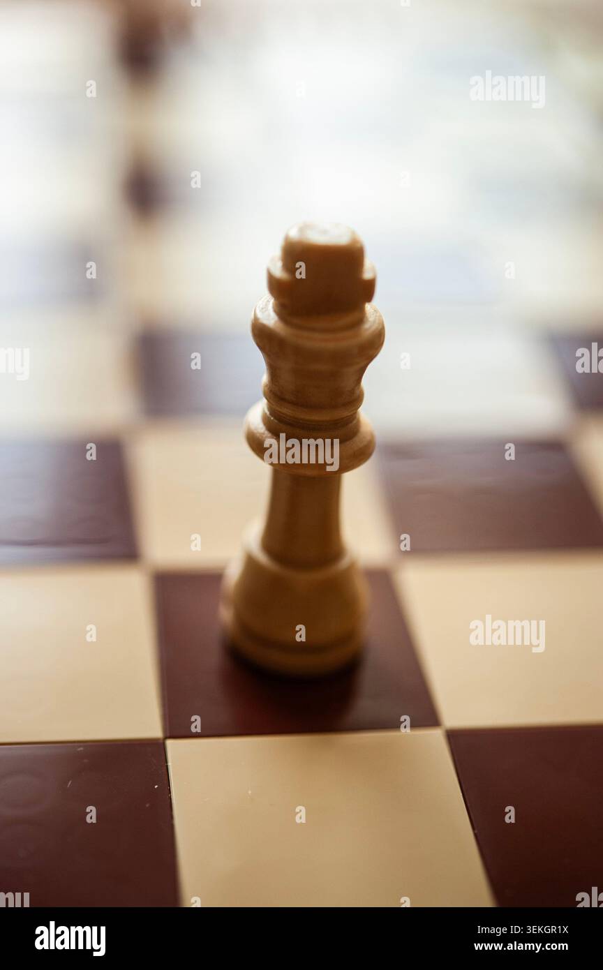 Roi d'échecs en bois seul sur échiquier, lumière chaude et mise au point peu profonde, concept de stratégie minimaliste Banque D'Images