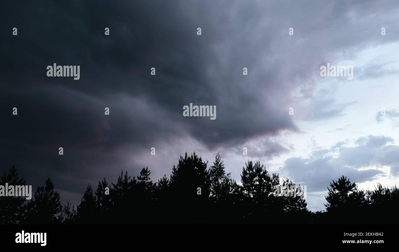 Orage dramatique avec nuages sombres dans la soirée. Ciel spectaculaire de nuages reflétant de fortes teintes d'orange, rose, bleu et jaune s'illuminant Banque D'Images