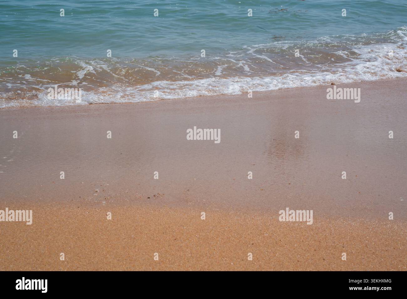De douces vagues se jettent sur une plage de sable à Sharm El Sheikh Egypte avec de l'eau claire le long du rivage de la mer Rouge en plein jour. Style de vie de station balnéaire. Banque D'Images