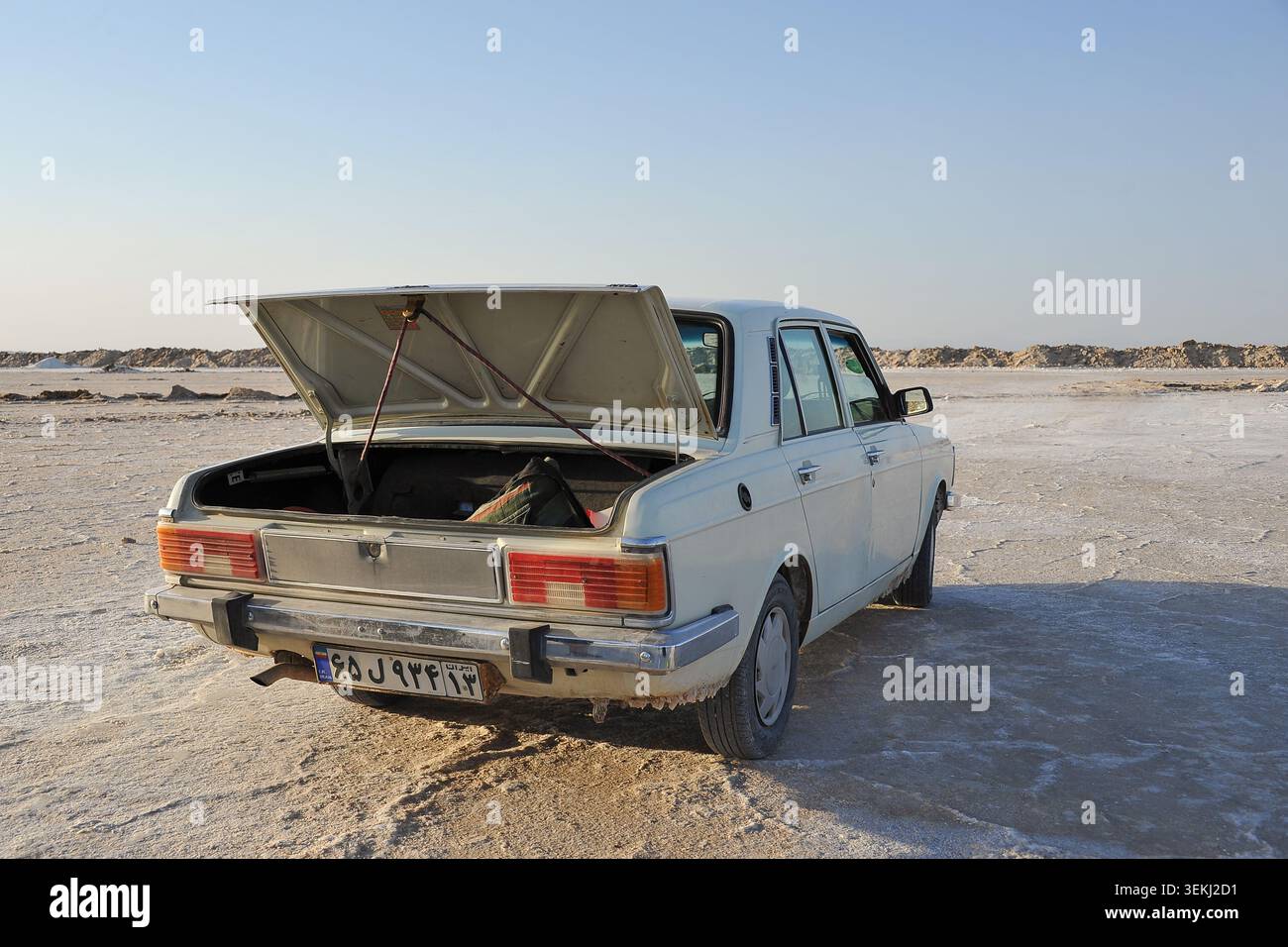 Berline vintage blanche avec coffre ouvert sur le désert de sel plat en Iran Banque D'Images