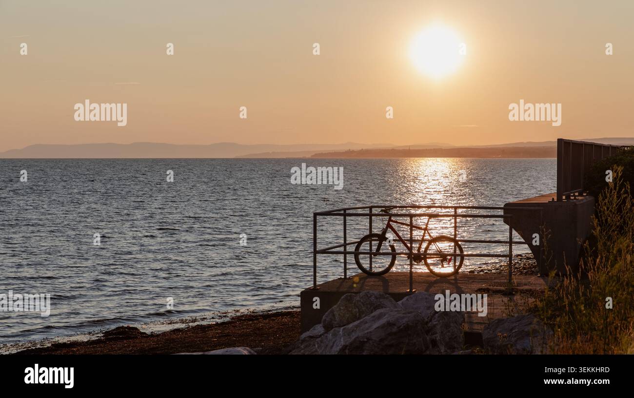 vue d'un vélo sur le côté de l'océan regardant à l'horizon avec le soleil brille sur Banque D'Images