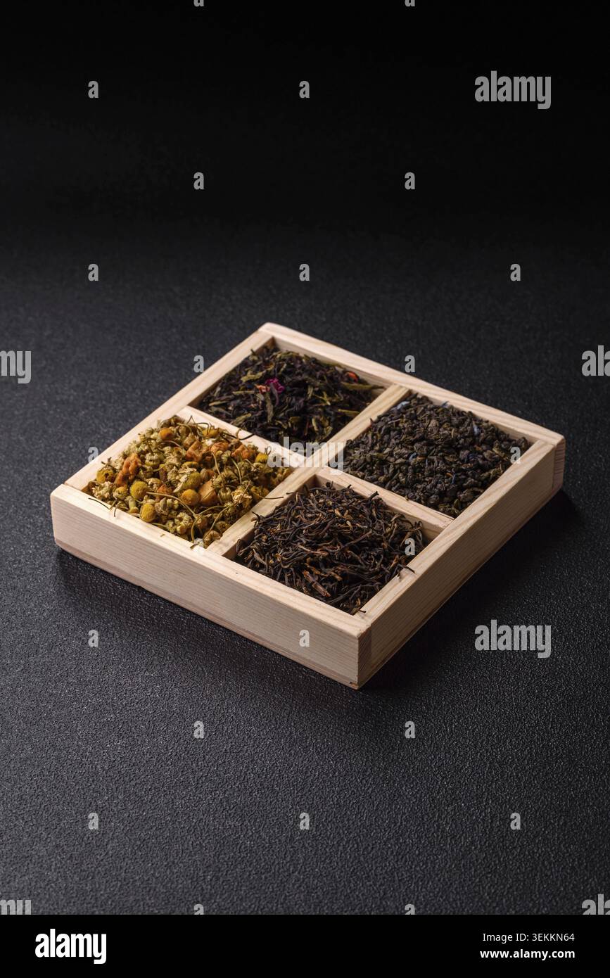 Une boîte en bois avec plusieurs types de thé séché, vert, noir, fruit, et camomille. Thé sec dans la boîte comme toile de fond pour votre conception Banque D'Images