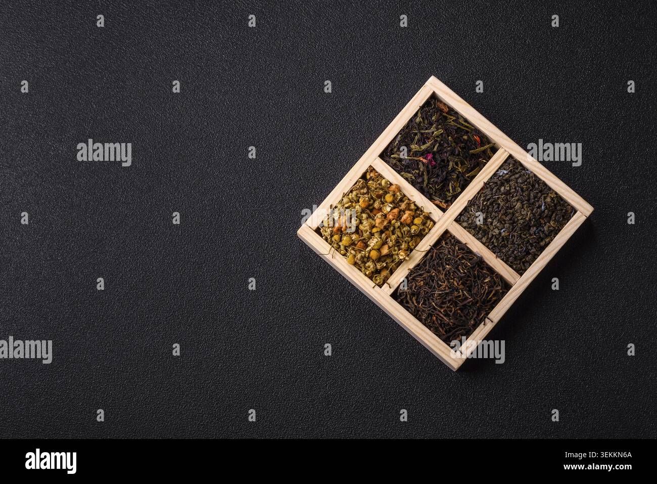 Une boîte en bois avec plusieurs types de thé séché, vert, noir, fruit, et camomille. Thé sec dans la boîte comme toile de fond pour votre conception Banque D'Images