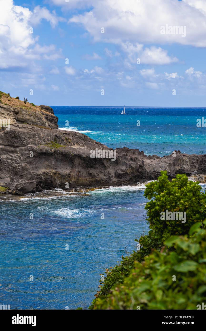 Majestueuse formation rocheuse émergeant de vagues turquoises vibrantes avec des vagues écrasantes. Banque D'Images