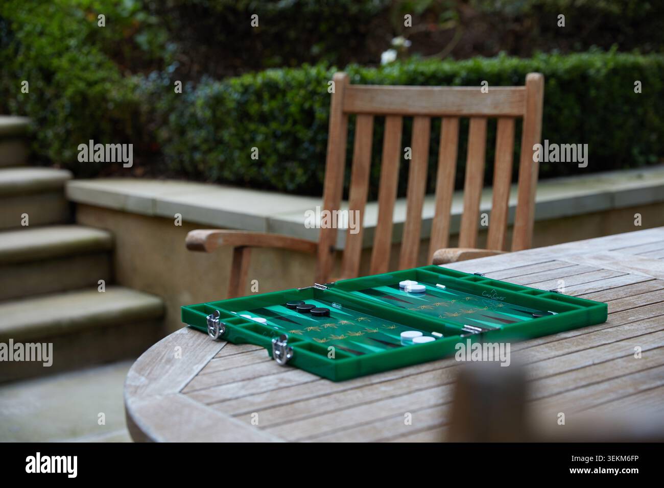 Plateau de backgammon vert installé sur une table de jardin en bois pour un jeu en plein air dans un cadre de patio privé. Banque D'Images
