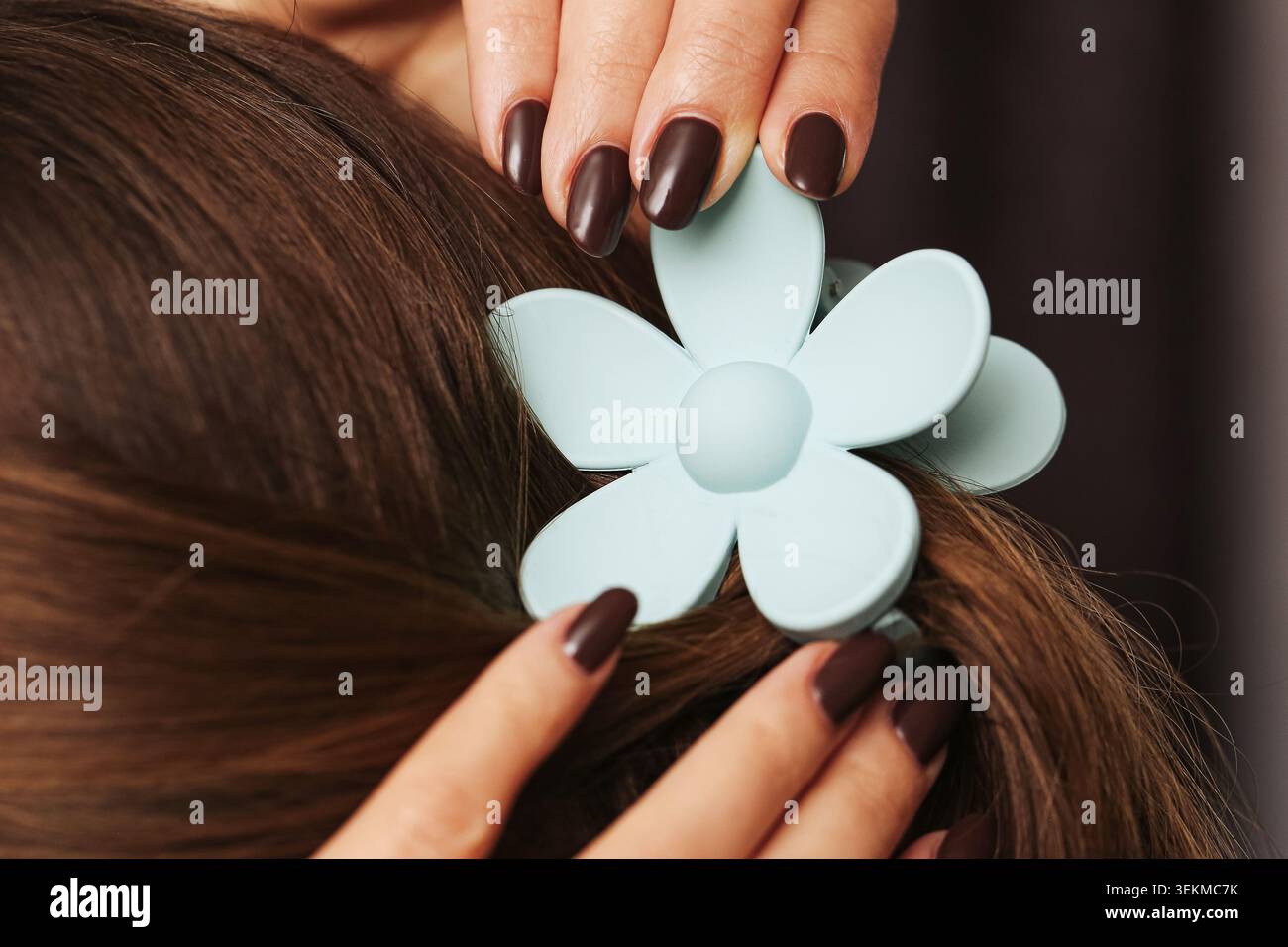 Femme attachant la pince à cheveux en forme de fleur à la coiffure gros plan. Accessoire de mode et concept de style de beauté avec ornement décoratif. Banque D'Images