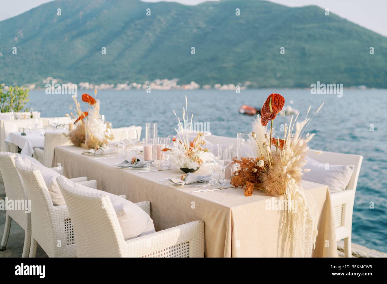 Arrangement pour dîner côtier. Ambiance balnéaire, décor floral et sièges confortables Banque D'Images