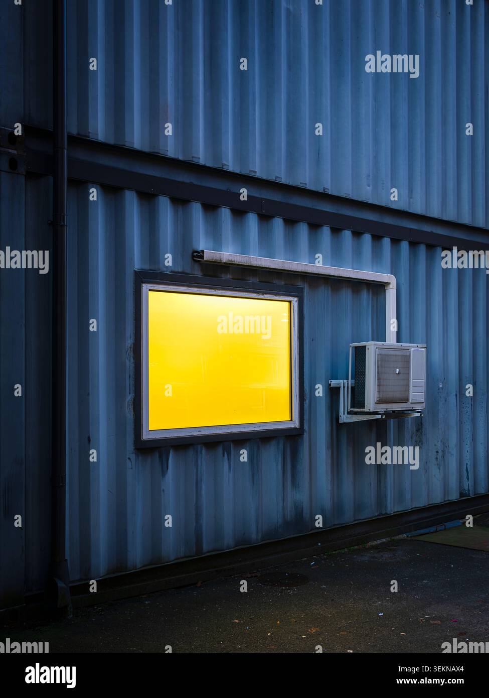 Unité AC à côté de la fenêtre éclairée sur le mur ondulé Banque D'Images