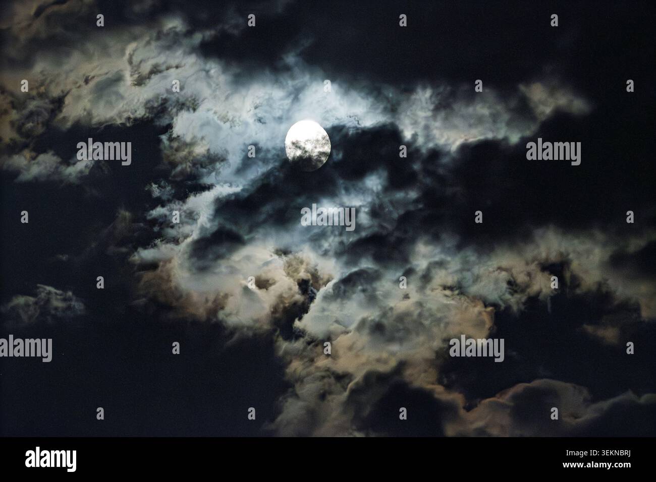 Par une nuit venteuse, une lune brillante jette son éclat tandis que les nuages de pluie courent à travers le ciel, créant une scène enchanteresse remplie de contrastes d'humeur et de fleétine Banque D'Images