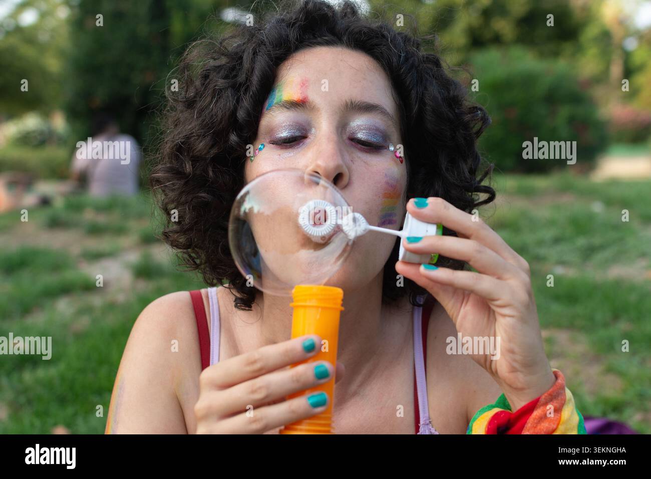 Personne avec le maquillage arc-en-ciel soufflant des bulles célébrant la fierté Banque D'Images