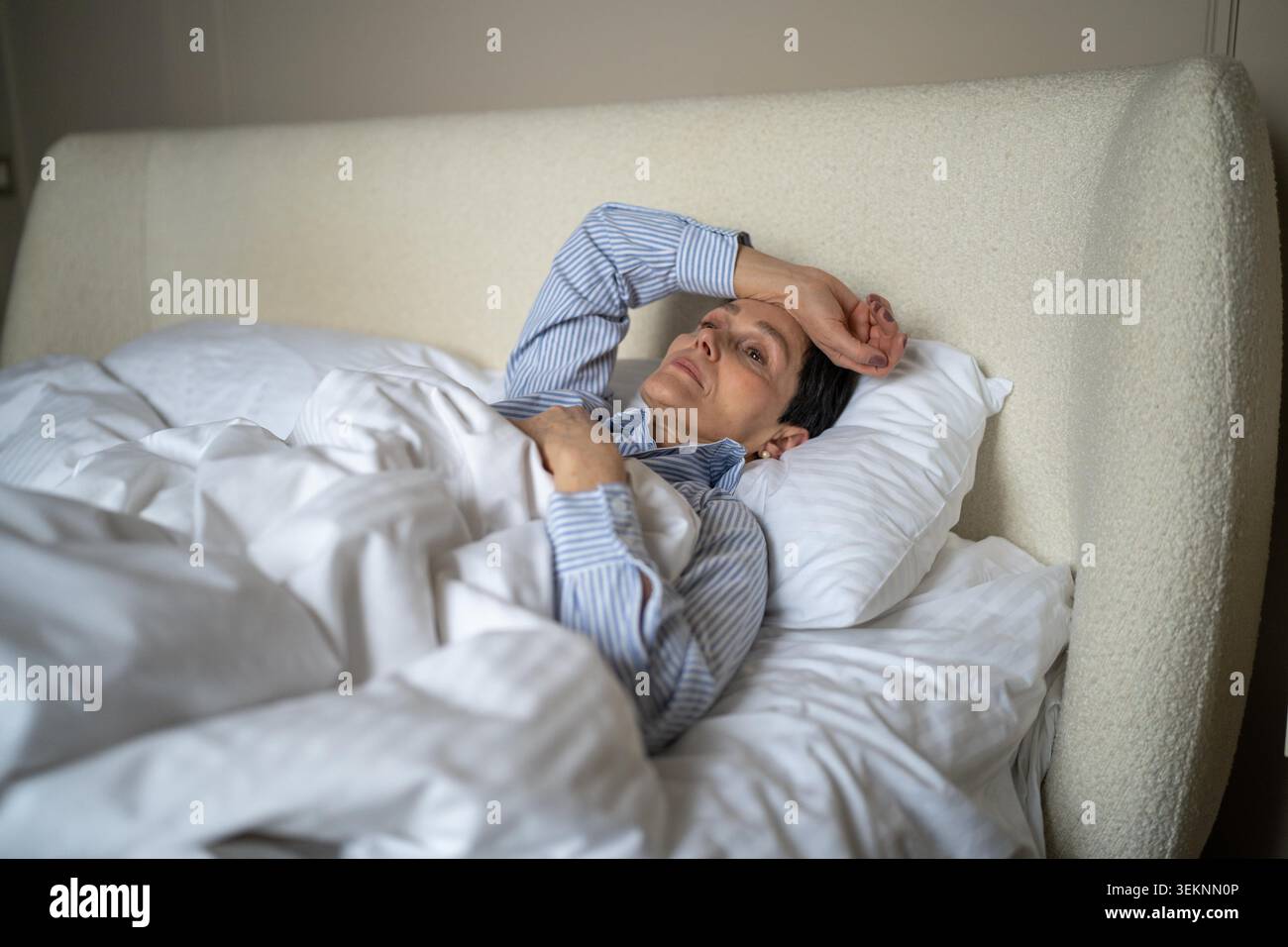 Malheureuse femme aînée réfléchie couchée au lit le matin à la maison avec une expression épuisée perdue, femme âgée dans la chambre montrant la solitude et la dépression à un âge plus avancé, crise de la vie et des problèmes mentaux. Banque D'Images