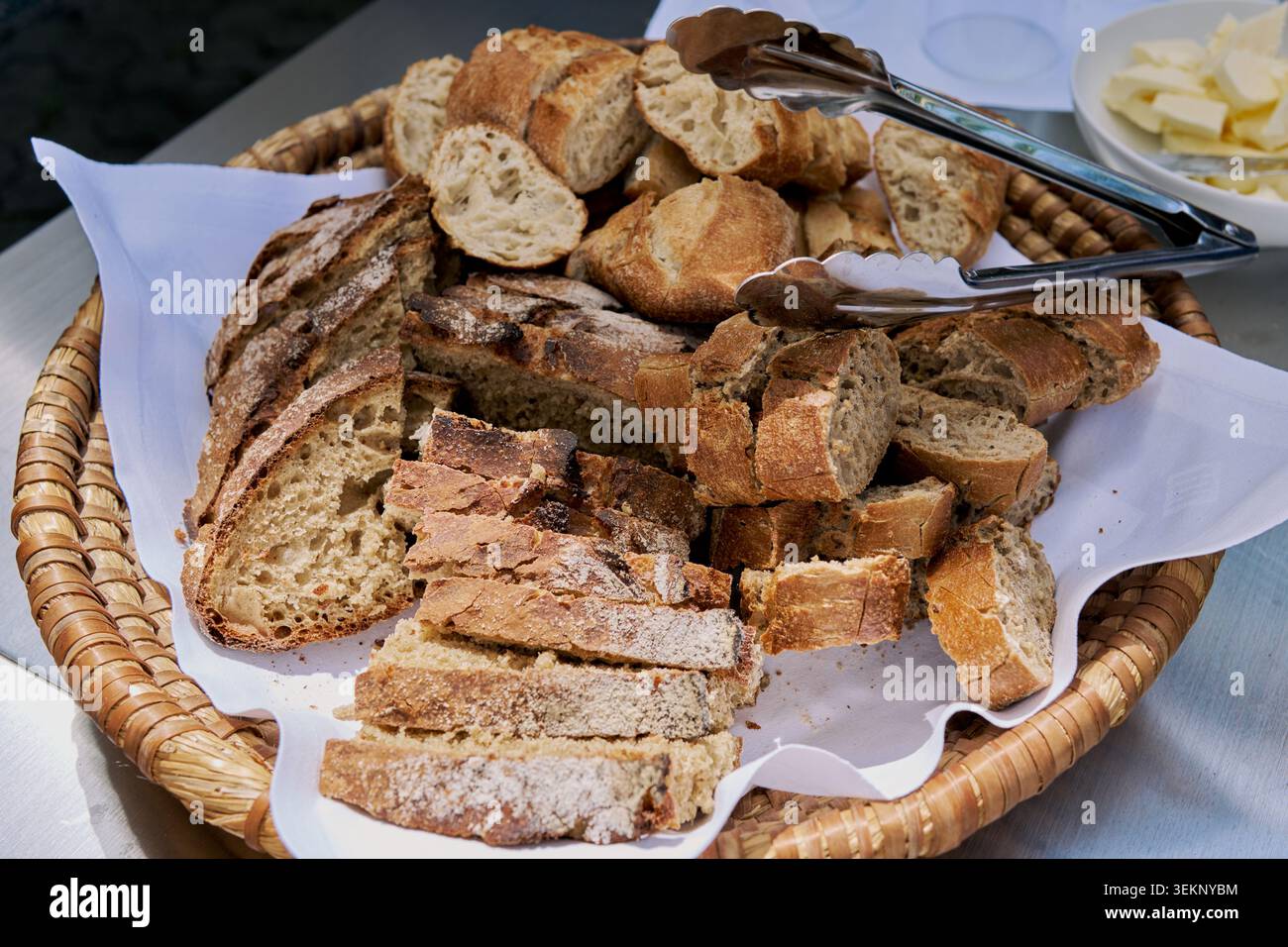 Assortiment de tranches de pain frais dans un panier en osier avec pinces. Banque D'Images