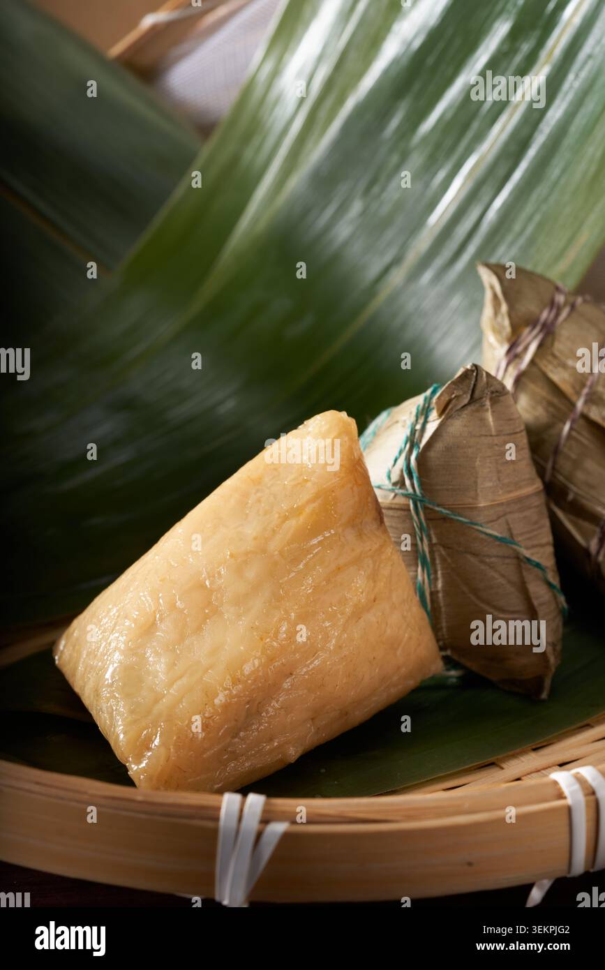 Les boulettes de riz à l'eau alcaline dorée pelées sont placées sur une plaque de bande de bambou et doublées de feuilles de boulettes de riz, créant un cristal clair et s. Banque D'Images