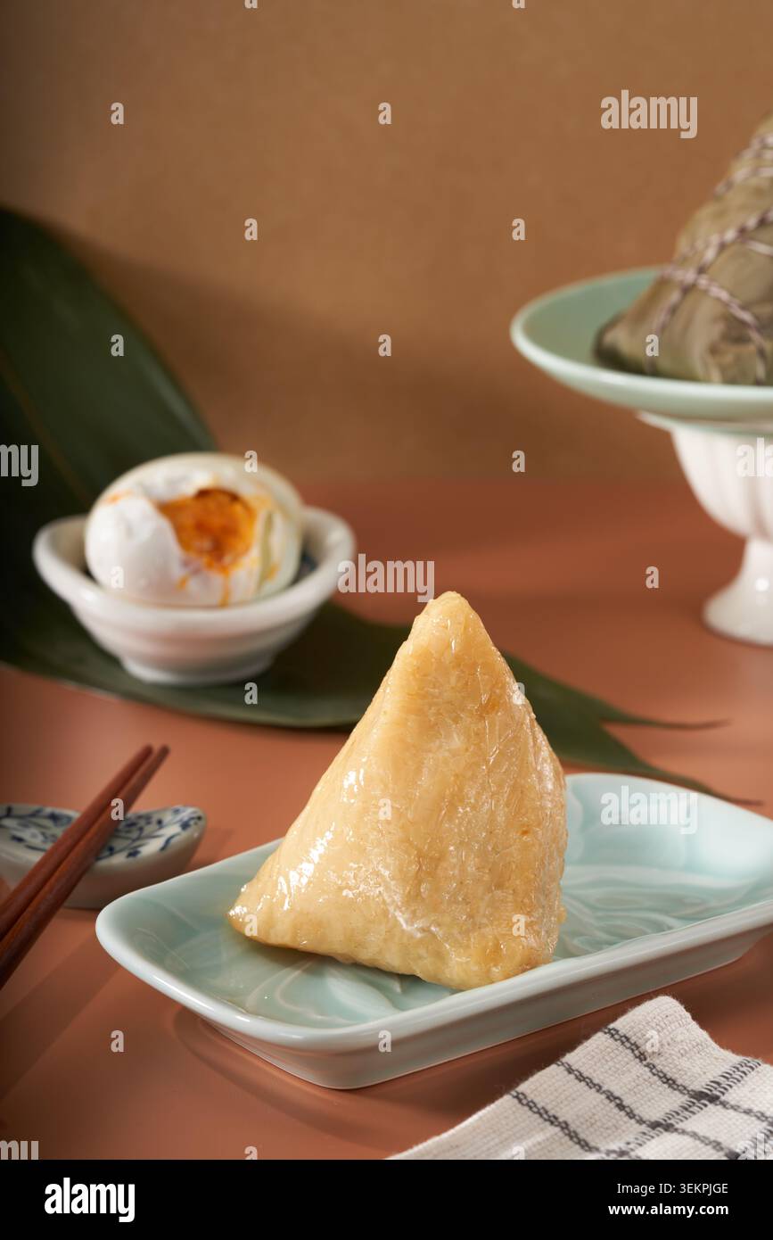 Boulettes triangulaires de riz à l'eau alcaline sur une assiette de céladon avec jaune d'œuf salé, une scène gastronomique chaleureuse pendant le Dragon Boat Festival Banque D'Images