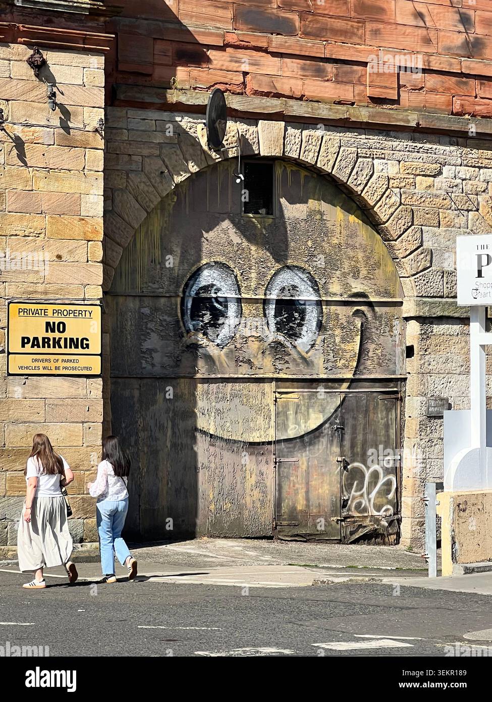 Femmes passant devant une paire d'yeux à Paisley Renfrewshire, ce graffiti bien connu est de l'artiste de Glasgow PSA, Banque D'Images