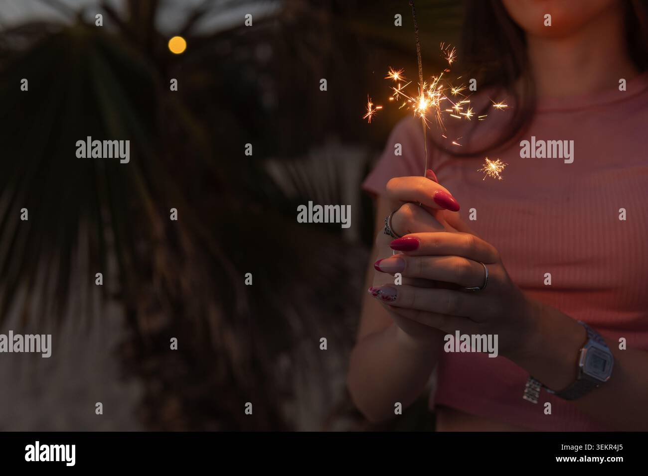 Une femme tient un étincelant dans sa main. L'image a un air chaleureux et festif, des célébrations et des occasions spéciales. Banque D'Images