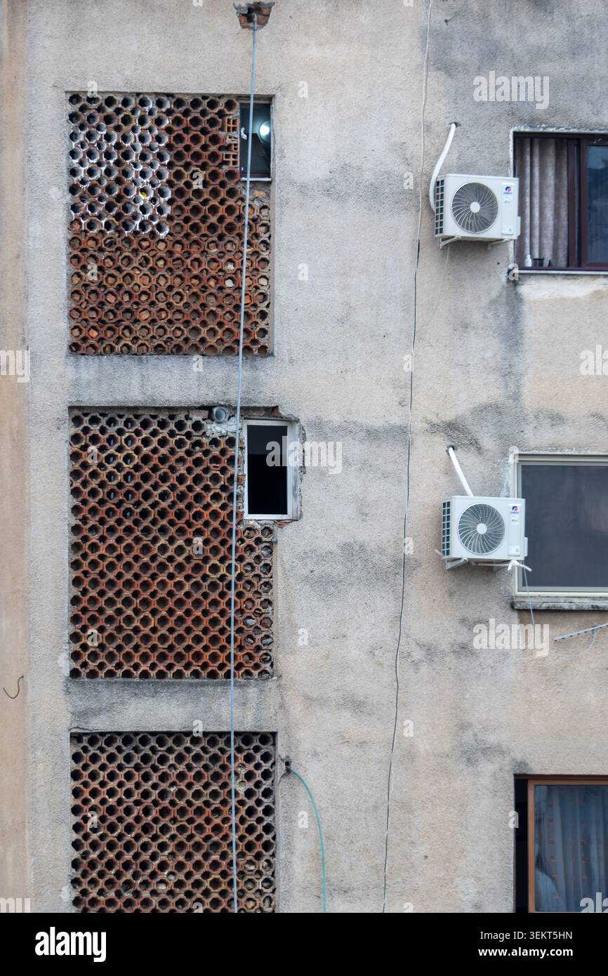 Vue d'une façade d'immeuble d'appartements altérée avec des écrans décoratifs en terre cuite et des unités de climatisation externes à Tirane, comté de Tirana, Al Banque D'Images