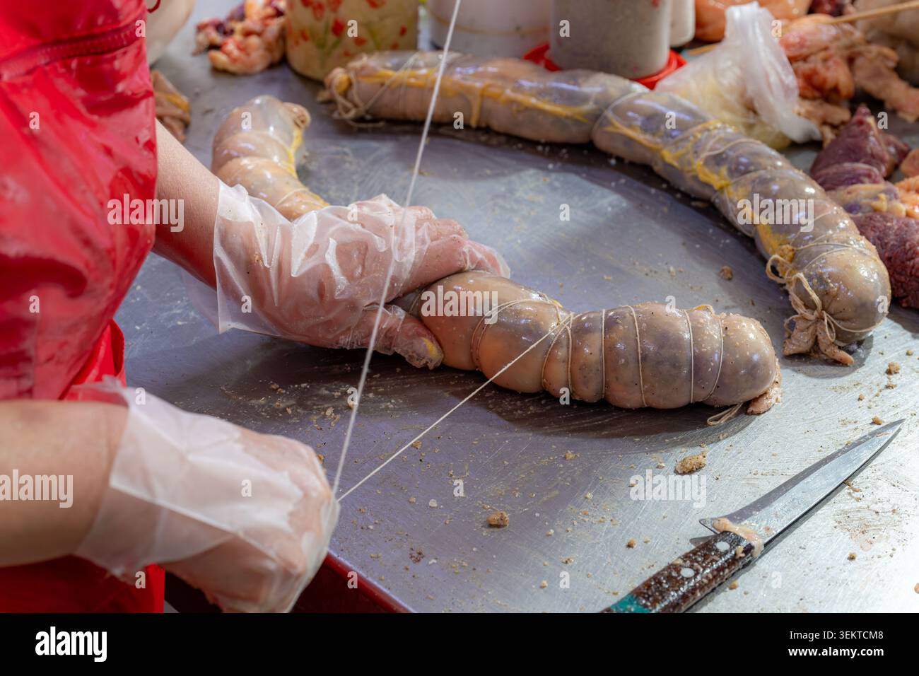 Gros plan des mains attachant et préparant la saucisse traditionnelle de viande de cheval kazy d'Asie centrale à un comptoir de marché à Bichkek. Banque D'Images