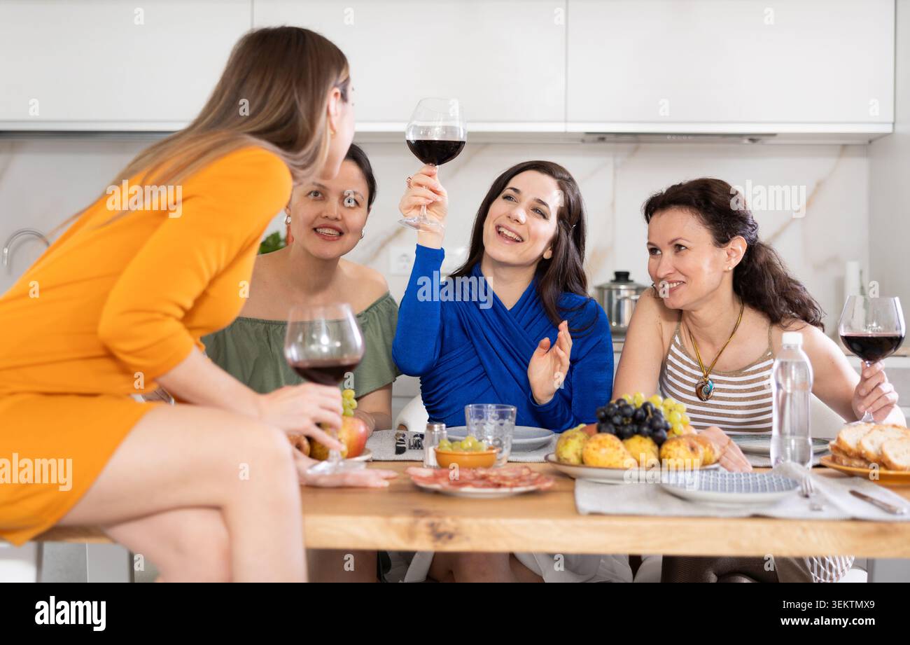 Des femmes heureuses se sont rassemblées autour d'une table festive ; participant à des discussions animées et appréciant les délices du vin Banque D'Images
