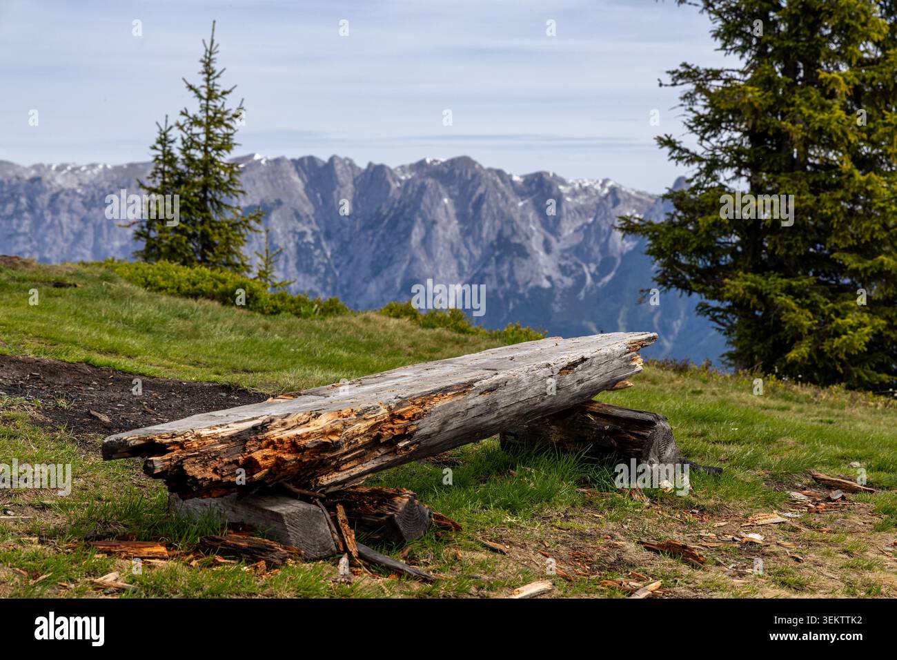 Un banc en bois rustique se trouve sur une colline herbeuse, offrant une vue panoramique sur les montagnes majestueuses en arrière-plan. Le banc est fait d'un grand, w Banque D'Images