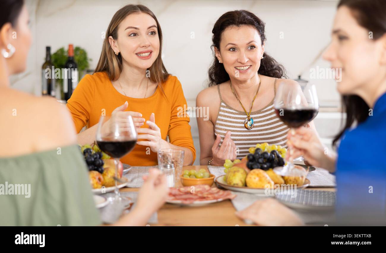 Des femmes heureuses se sont rassemblées autour d'une table festive ; participant à des discussions animées et appréciant les délices du vin Banque D'Images