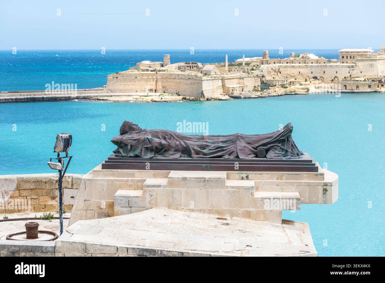 La Valette, Malte – 16 mai 2025 : vue panoramique sur la côte du Mémorial de la seconde Guerre mondiale de Siege Bell surplombant les fortifications historiques et l'Wate turquoise Banque D'Images