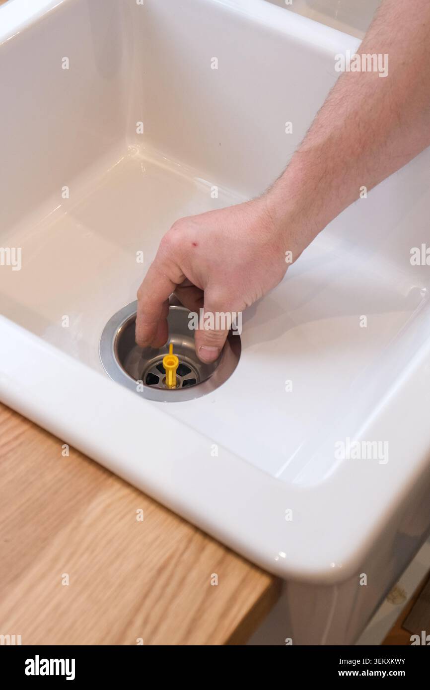 Retirer à la main le bouchon jaune du drain blanc de l'évier Banque D'Images