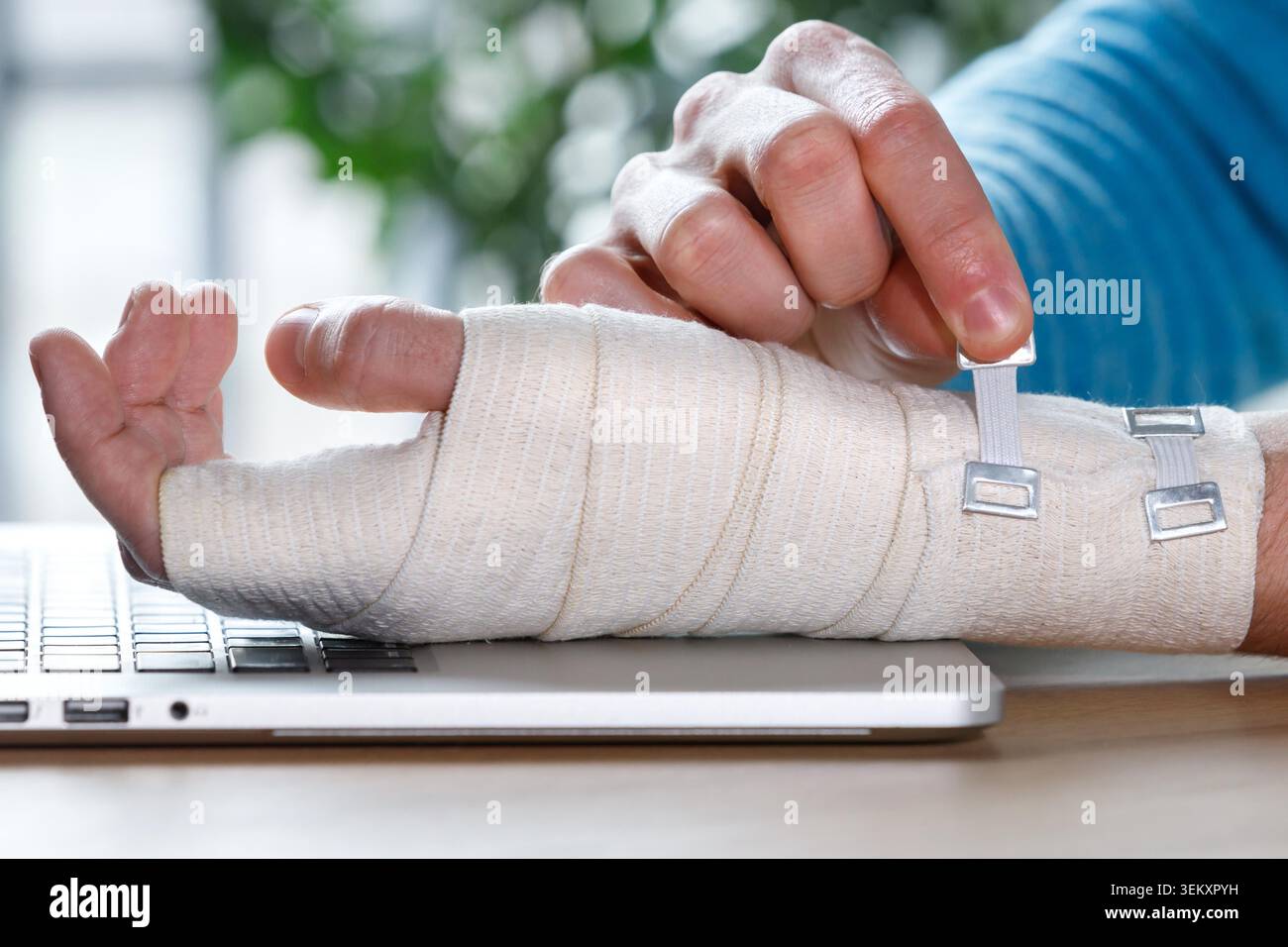 Gros plan des bras de l'homme enveloppant son poignet douloureux avec un bandage orthopédique élastique flexible de soutien causé par un travail prolongé sur un ordinateur portable. Syndrome du canal carpien, arthrite, syndrome de la branche. Banque D'Images
