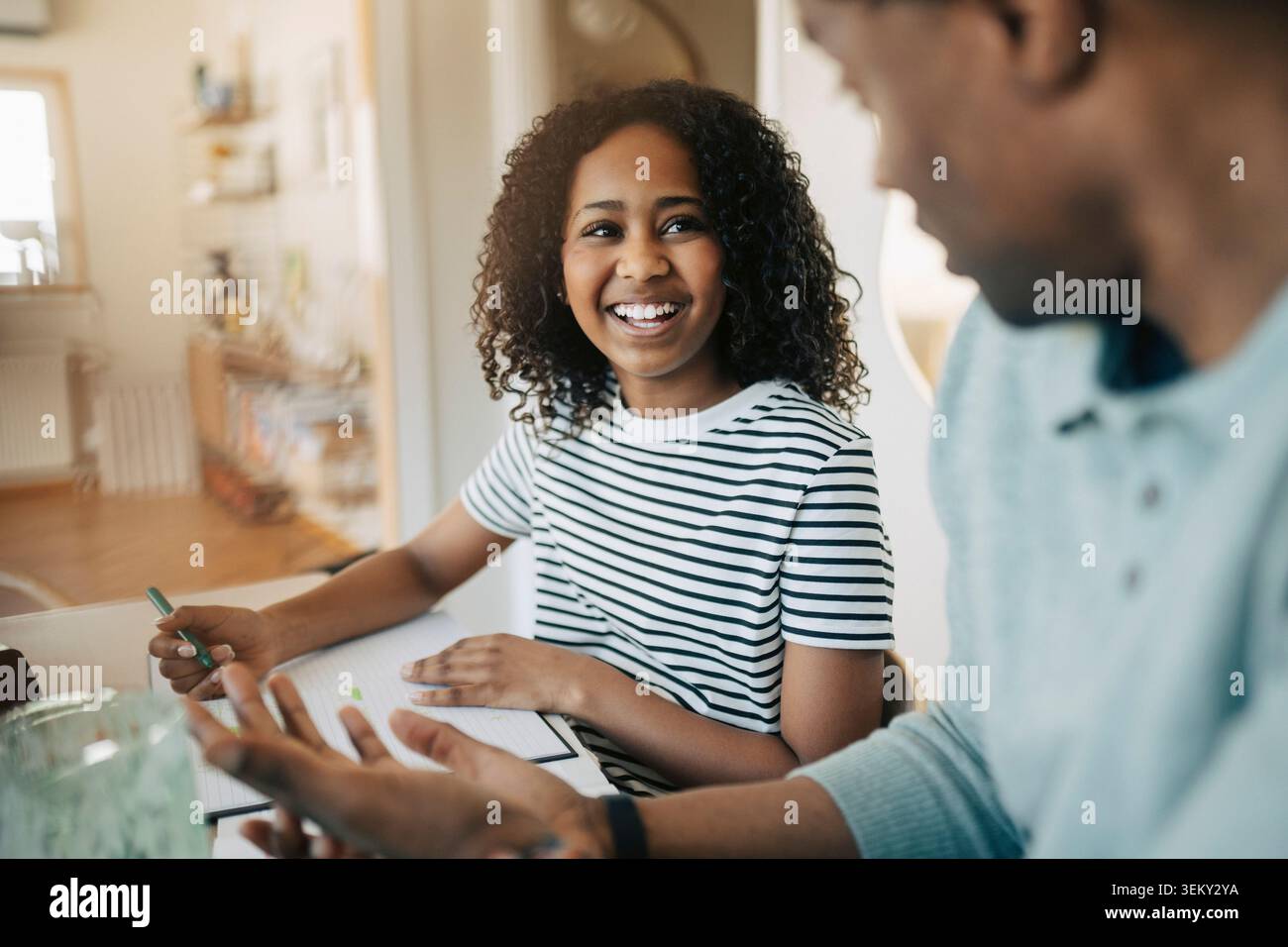 Fille heureuse parlant avec le père pendant la session d'étude à domicile Banque D'Images