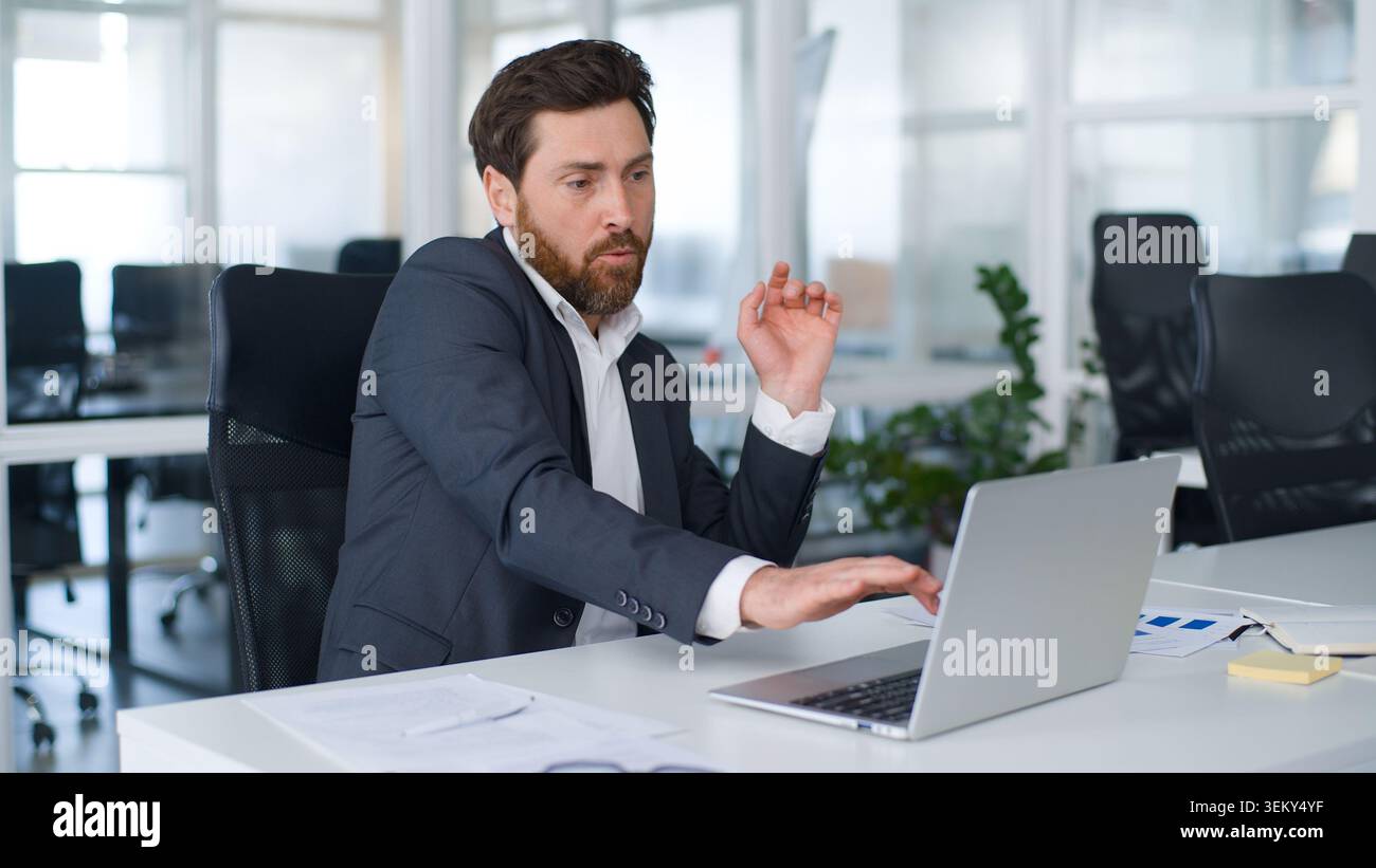 Homme d'affaires caucasien d'âge moyen motivé tapant clavier d'ordinateur portable dansant avec de la musique dans l'entreprise homme d'affaires mature professionnel masculin Banque D'Images