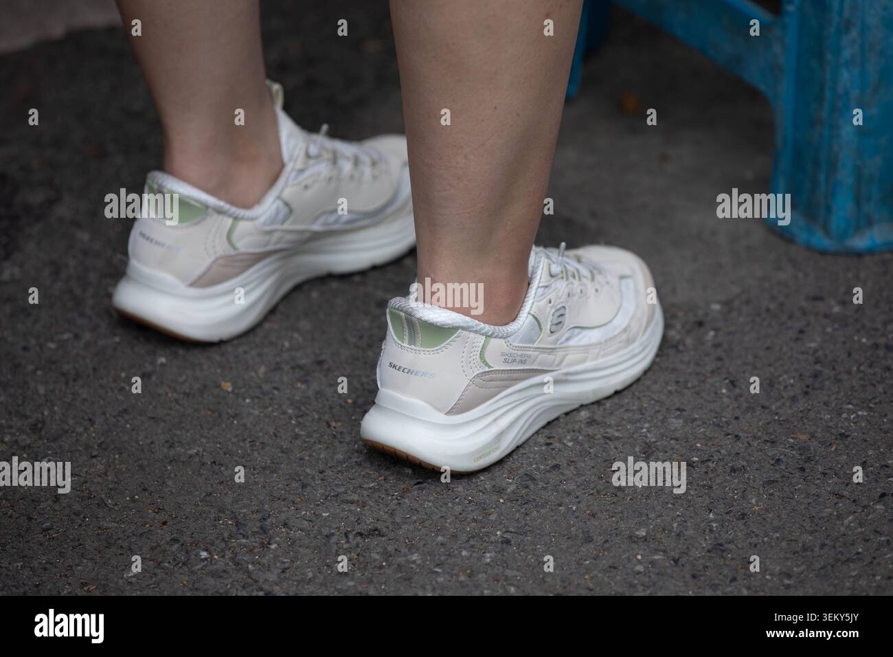 BANGKOK, THAÏLANDE - 17 MAI 2026 : femme en baskets blanches debout sur le sol lors des achats de marchandises, vue en angle élevé Banque D'Images