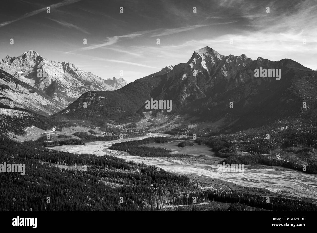 Vue panoramique sur une vaste vallée de montagne avec une rivière sinueuse et une forêt dense sous un ciel spectaculaire Banque D'Images