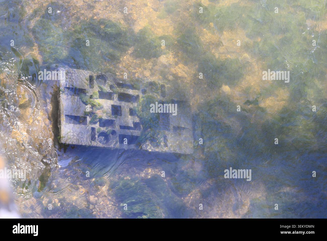 Une plaque de base pour monter des panneaux de signalisation a été jetée dans une rivière. Banque D'Images