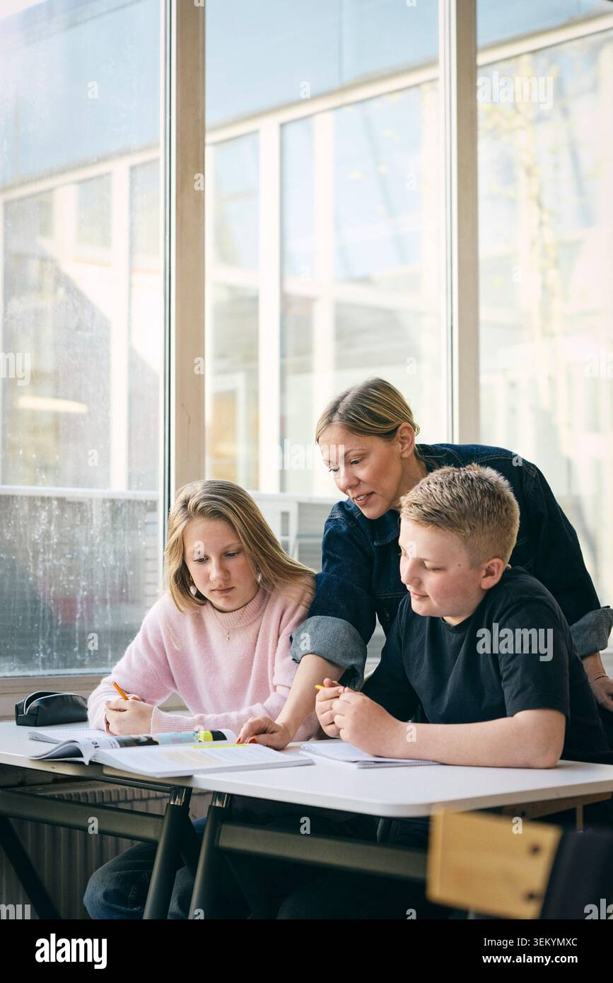 Enseignante guidant les élèves avec des études en classe au collège Banque D'Images