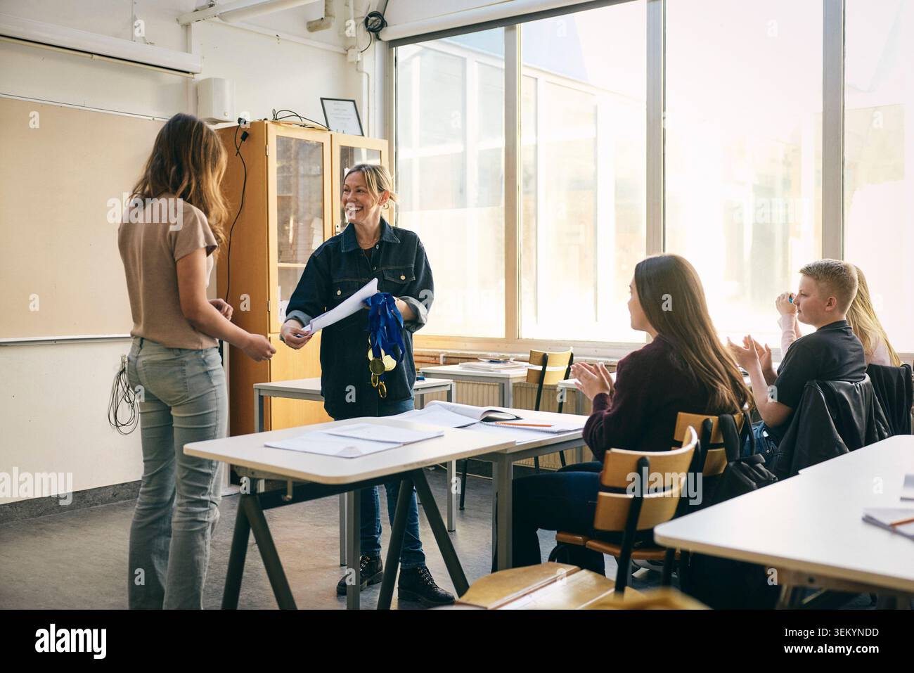 Heureux enseignant donnant certificat à une étudiante en classe à l'école Banque D'Images