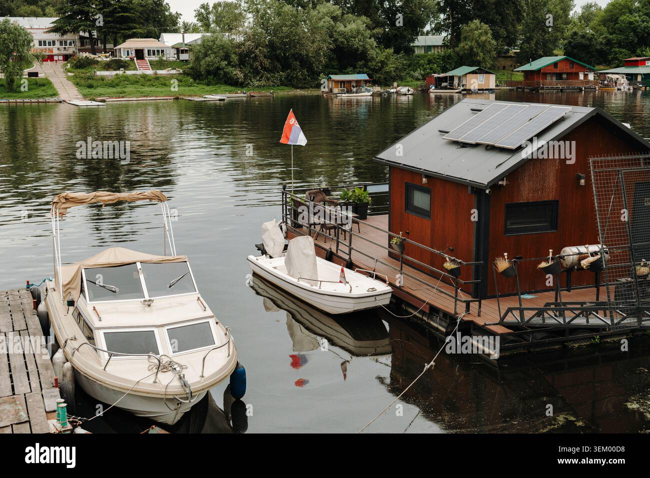 Une maison flottante au bord de la rivière dispose de panneaux solaires et d'un quai privé. La vie durable rencontre les loisirs dans un cadre calme en bord de mer. Banque D'Images