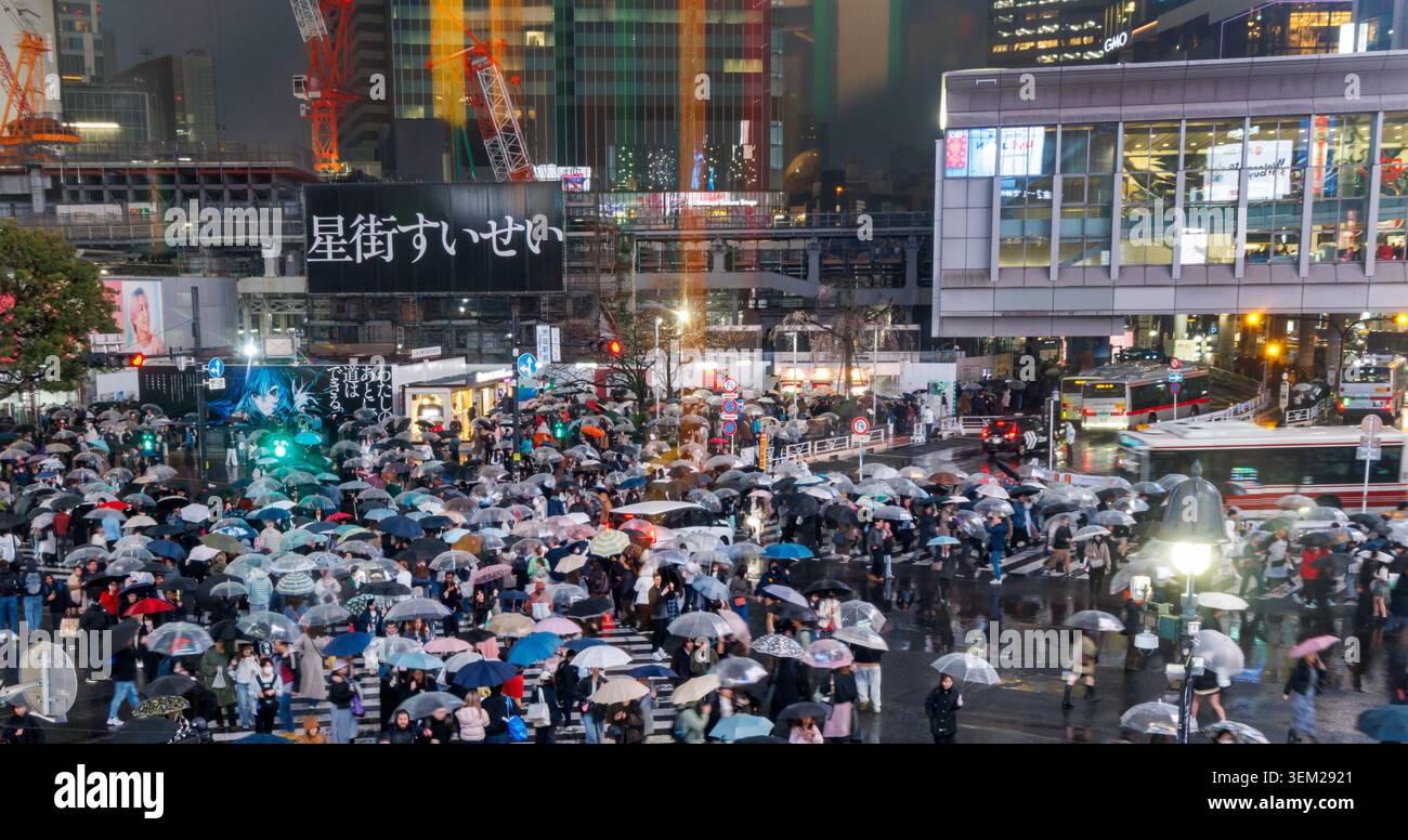 Des foules de piétons porteurs de parapluies traversent Shibuya Scramble Crossing sous la pluie la nuit, Tokyo, Japon Banque D'Images
