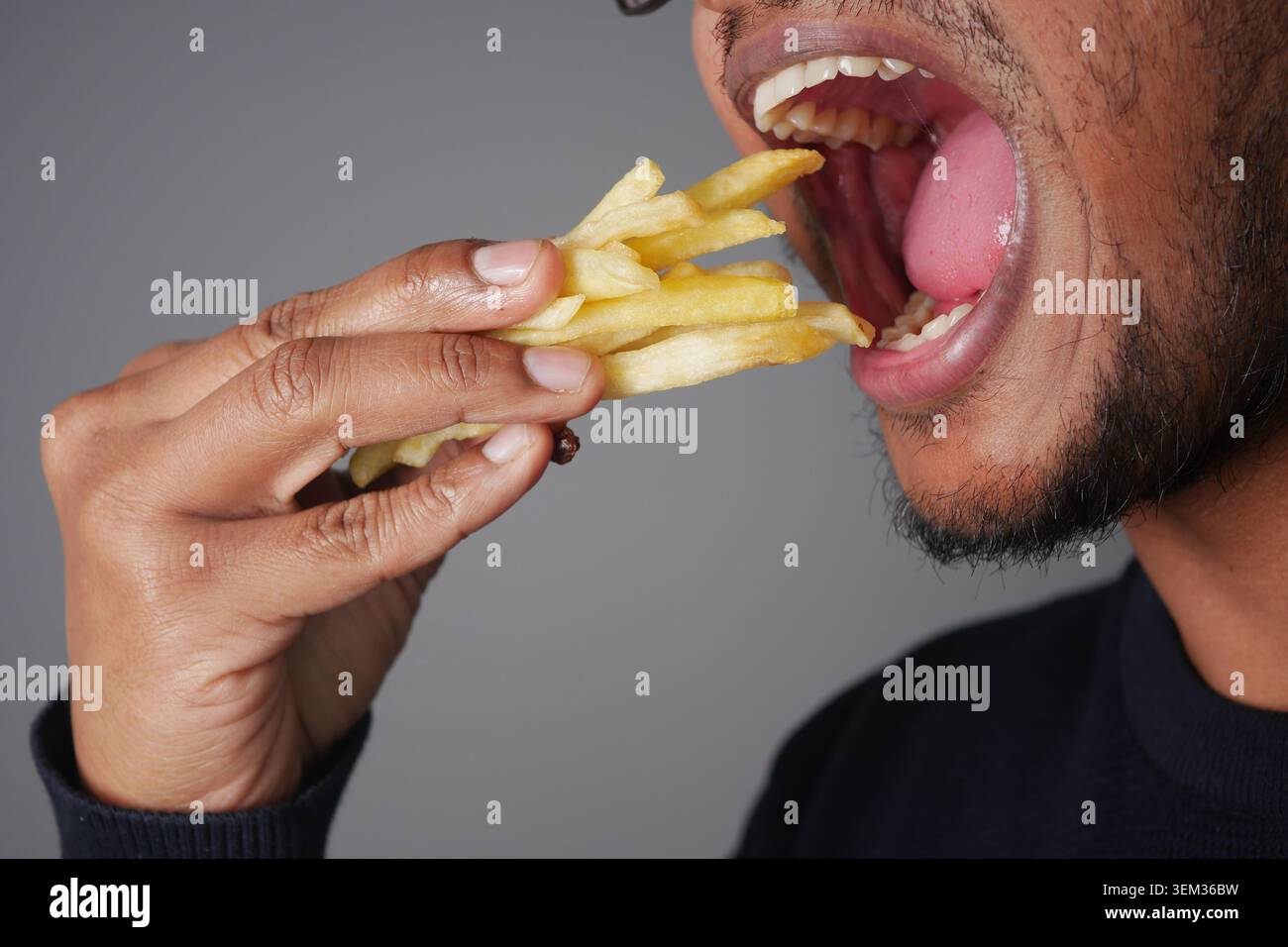 L'homme mange des frites en gros plan de la main et de la bouche Banque D'Images