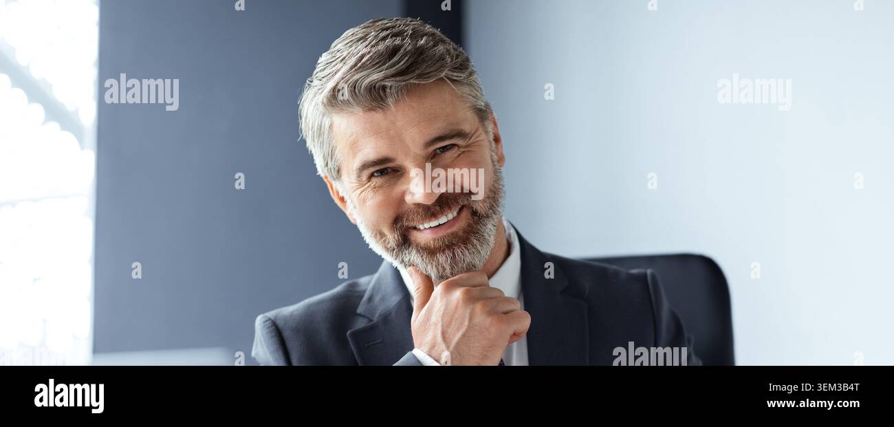 Heureux homme aux cheveux gris souriant à la caméra dans le bureau moderne, Business concept Banque D'Images