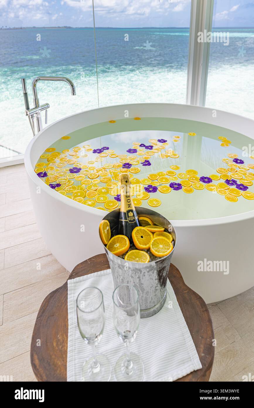 Baignoire de suite de lune de miel tropicale avec des pétales de fleurs, des verres à champagne et vue sur l'océan. Luxe spa romantique. Voyage de resort, vacances, bien-être, couple Banque D'Images