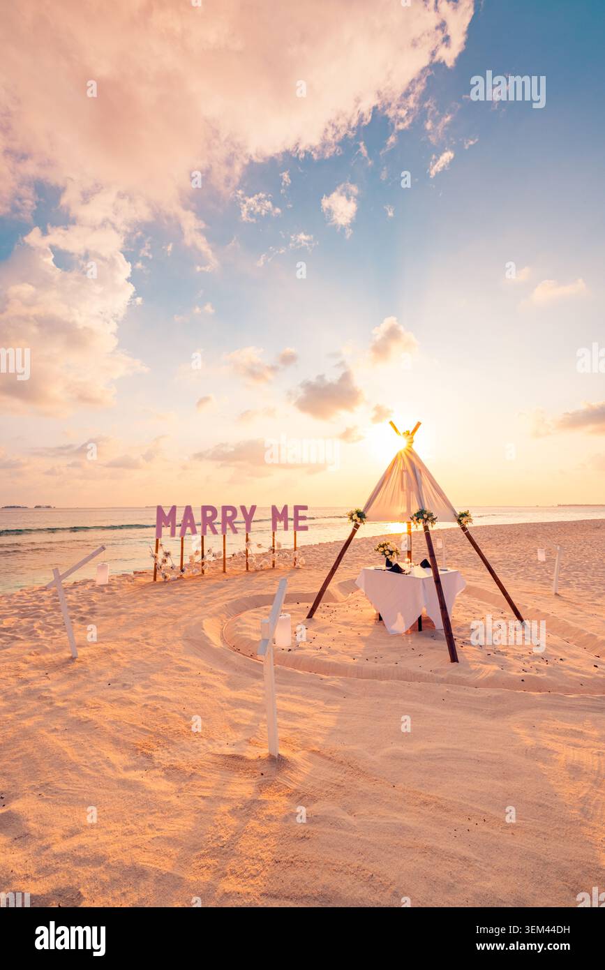 Panneau romantique de demande en mariage sur la plage, mise en scène pour une proposition de mariage. Décoration de tipis avec palmiers sous un coucher de soleil tropical. Scène de célébration pour les fiançailles et la lune de miel Banque D'Images
