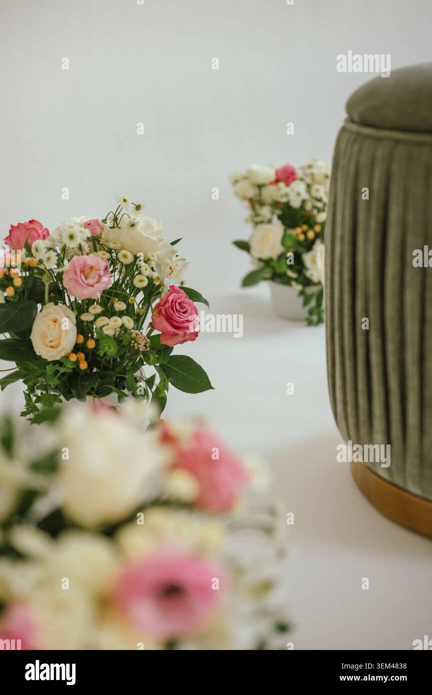 Bouquets floraux élégants à côté d'un pouf vert sur fond blanc Banque D'Images