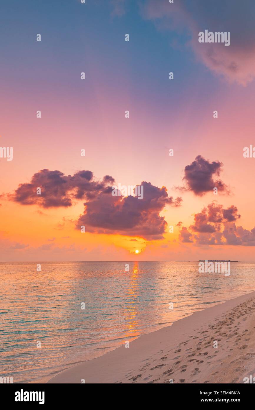 Ciel pastel vif coucher de soleil calme rivage. Scène de paume verticale dérivant des nuages. Plage tropicale rêveuse retraite douce au crépuscule Banque D'Images
