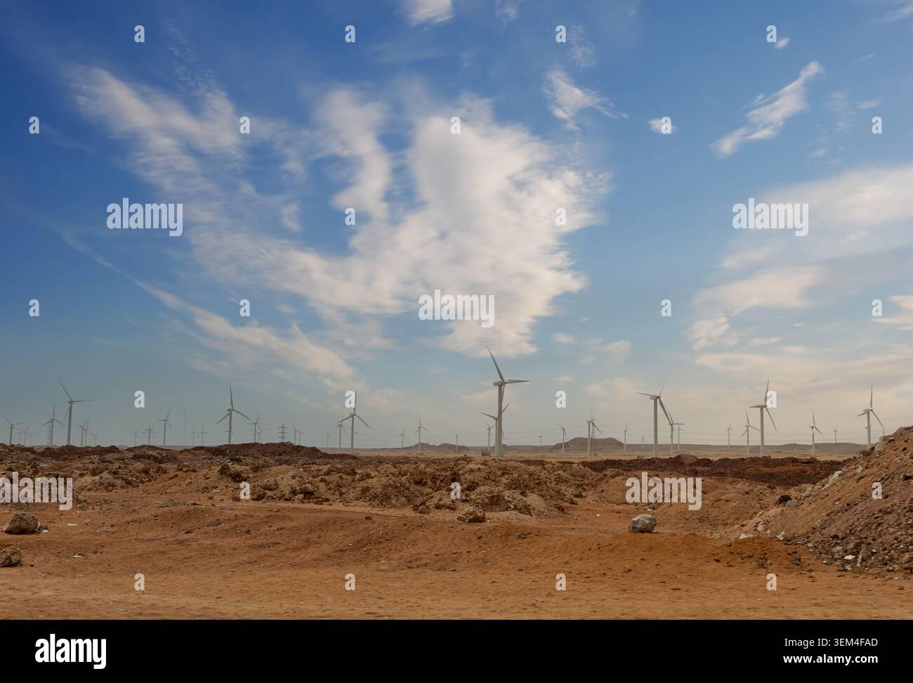 Ferme éolienne à grande échelle générant de l'énergie propre renouvelable sur un terrain désertique aride avec un sol rocheux exposé et une végétation clairsemée sous-jacente Banque D'Images