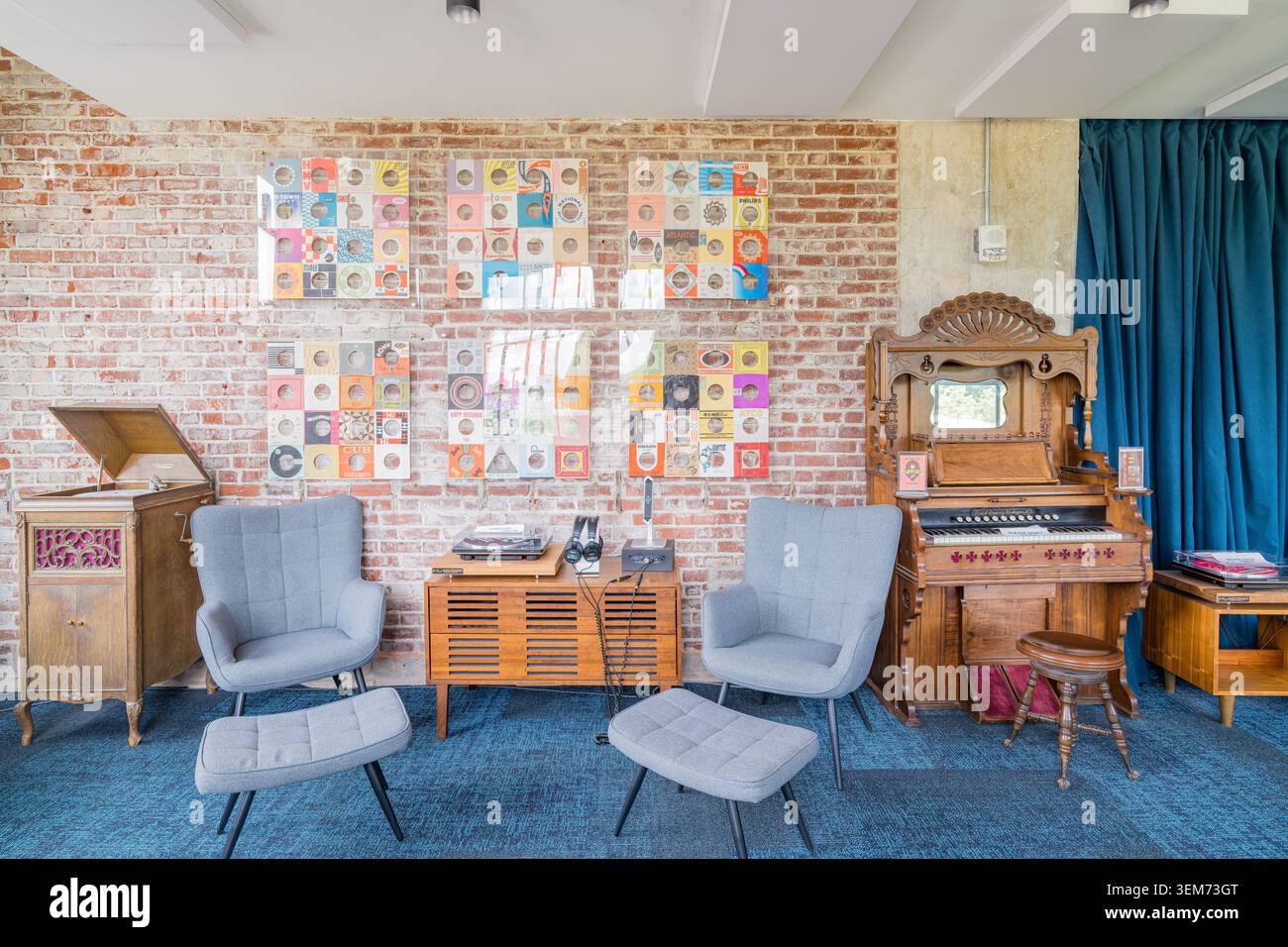 Memphis, États-Unis, 24 MAI 2026 - Intérieur d'un lounge musical rétro avec des murs en briques apparentes, des meubles en bois vintage et des fauteuils bleus Banque D'Images