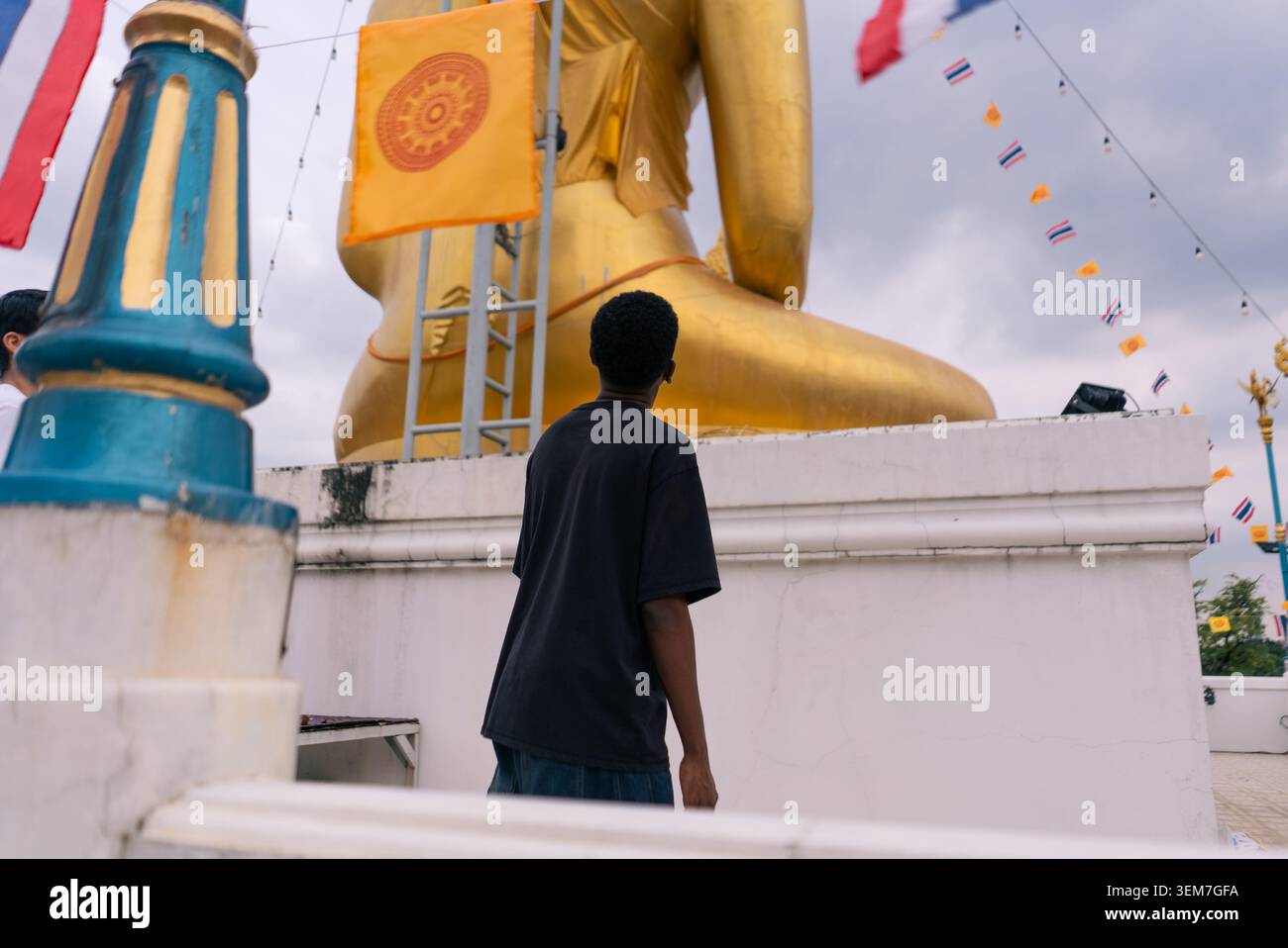 Personne observant une grande statue dorée de bouddha, contemplant la spiritualité au temple Banque D'Images